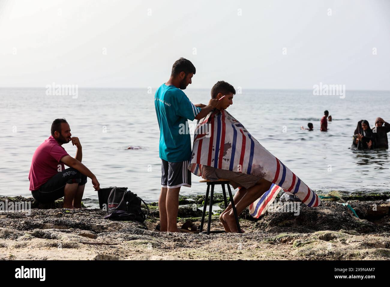 20 mai 2024 : Deir al-Balah, bande de Gaza, Palestine. 20 mai 2024. Un palestinien se fait couper les cheveux sur une plage près de Deir al-Balah, au centre de la bande de Gaza, qui est en proie à des assauts. Malgré plus de sept mois de violents bombardements israéliens et aucun endroit sûr dans l'enclave palestinienne, les habitants de Gaza visitent le front de mer pour un bref répit après la guerre et la chaleur intense de leurs tentes à proximité (crédit image : © Adel Al Hwajre/IMAGESLIVE via ZUMA Press Wire) USAGE ÉDITORIAL SEULEMENT! Non destiné à UN USAGE commercial ! Banque D'Images