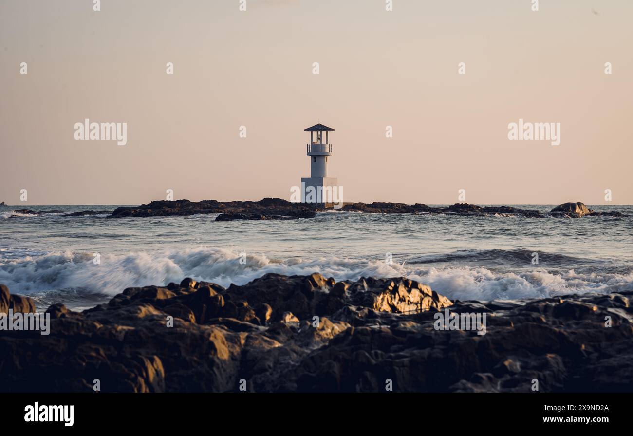 Phare entouré d'eau et ciel nuageux coucher de soleil Banque D'Images