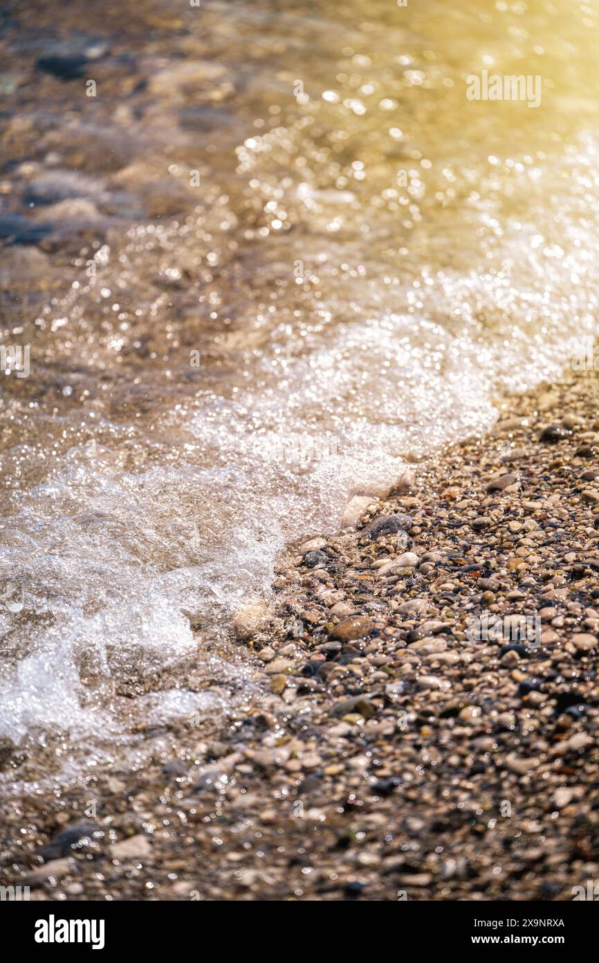 Plage avec de petites pierres rondes multicolores par une journée ensoleillée Banque D'Images