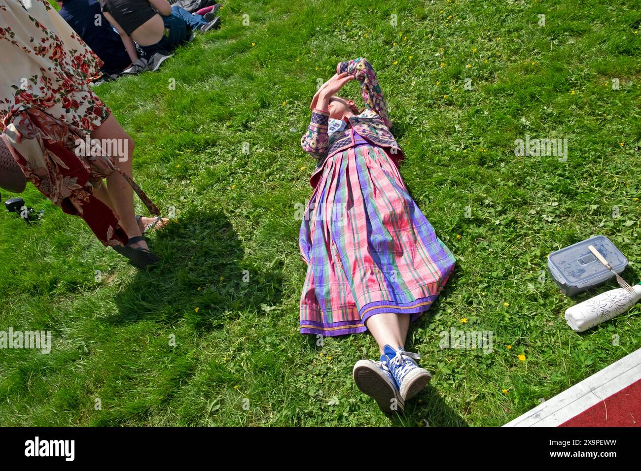 Jeune femme portant une belle jupe colorée couchée sur la pelouse de pelouse se relaxant sur le site de Hay Festiva à Hay-on-Wye Wales UK KATHY DEWITT Banque D'Images