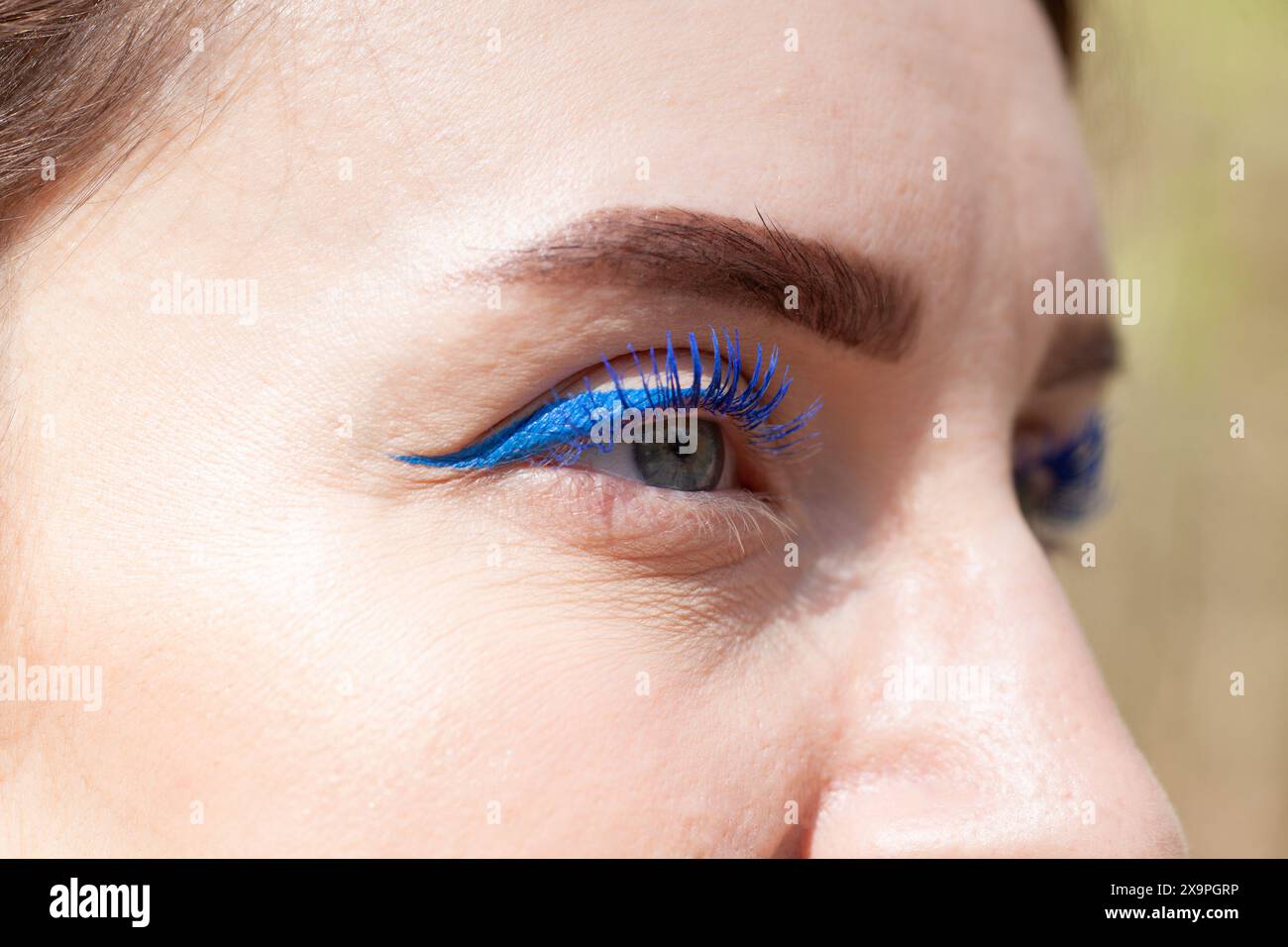 Gros plan de l'oeil d'une femme avec eye-liner bleu et mascara, mettant en valeur des détails de maquillage éclatants Banque D'Images