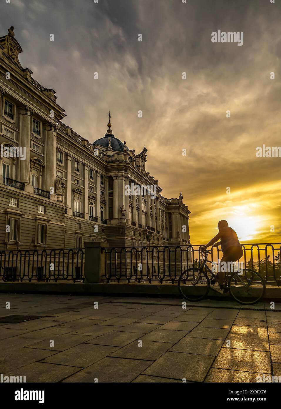 Un motard mûr profitant d'un coucher de soleil face au Palais Royal de Madrid. Banque D'Images