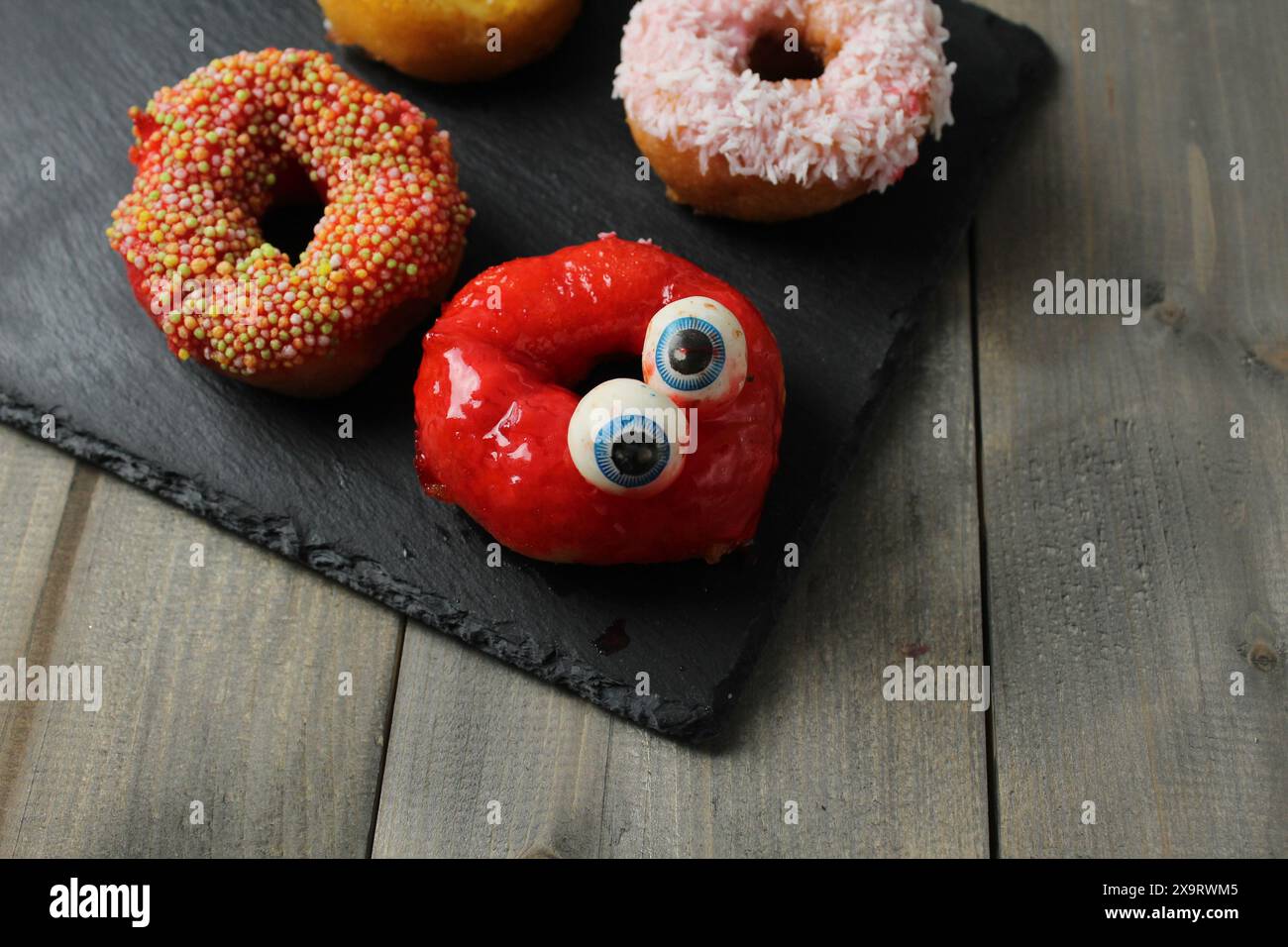 Donat dessert avec des yeux drôles sur un fond gris avec un espace pour le texte copyspace. Concept de célébration d'Halloween. Banque D'Images