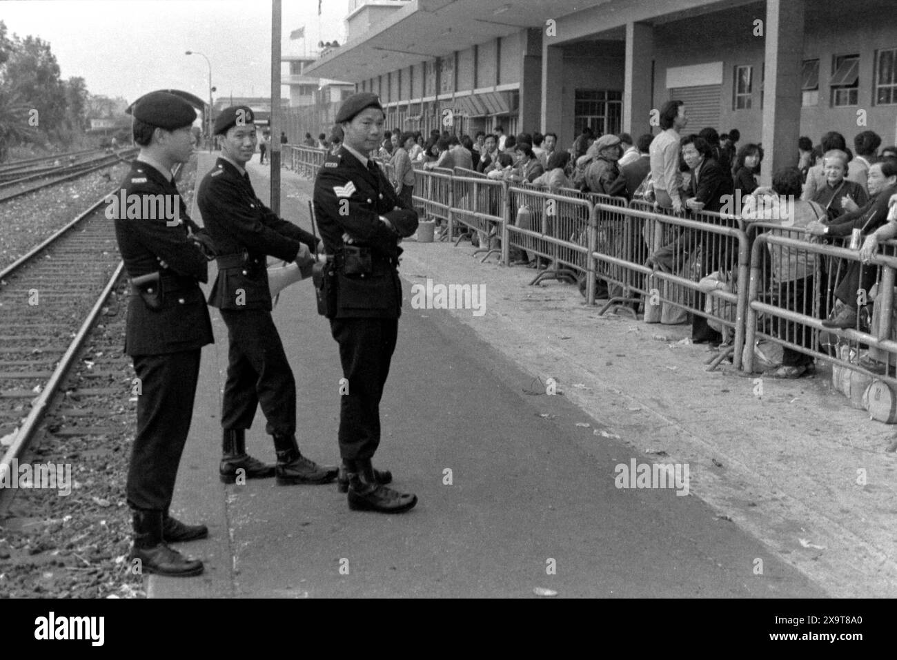 Passagers attendant un train diesel en direction du sud, gare de Lo Wu, chemin de fer de Kowloon-Canton, Hong Kong, nouvel an lunaire 1981. La foule qui attend vient de rentrer à Hong Kong de Chine continentale. Les policiers sur le quai sont engagés dans la gestion des foules, en raison du nombre élevé de passagers de la saison des fêtes. C'était avant que la KCR soit électrifiée au début des années 1980 et que les stations et les installations soient modernisées. Banque D'Images