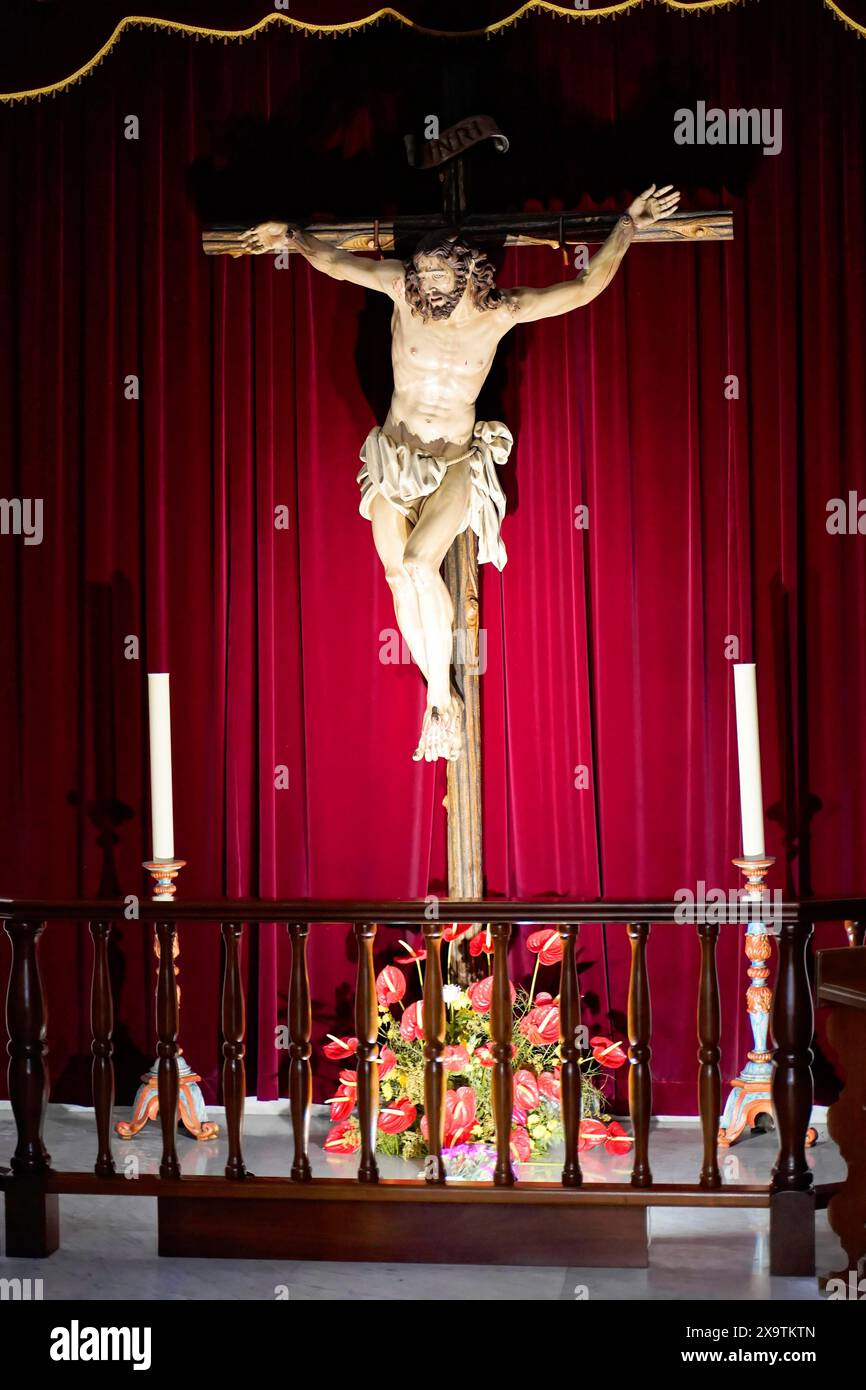 Basilica de Nuestra Senora, Candelaria, Tenerife, Îles Canaries, Espagne, Europe, crucifix en bois avec la figure de Jésus devant un rideau rouge profond Banque D'Images