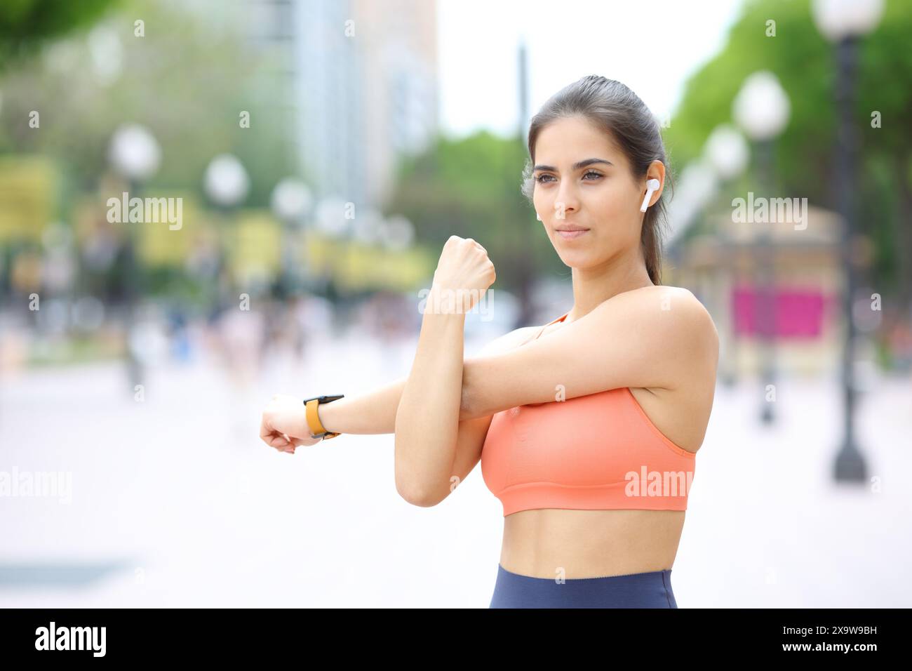 Coureur portant un écouteur écoutant de la musique étirant les bras dans la rue Banque D'Images