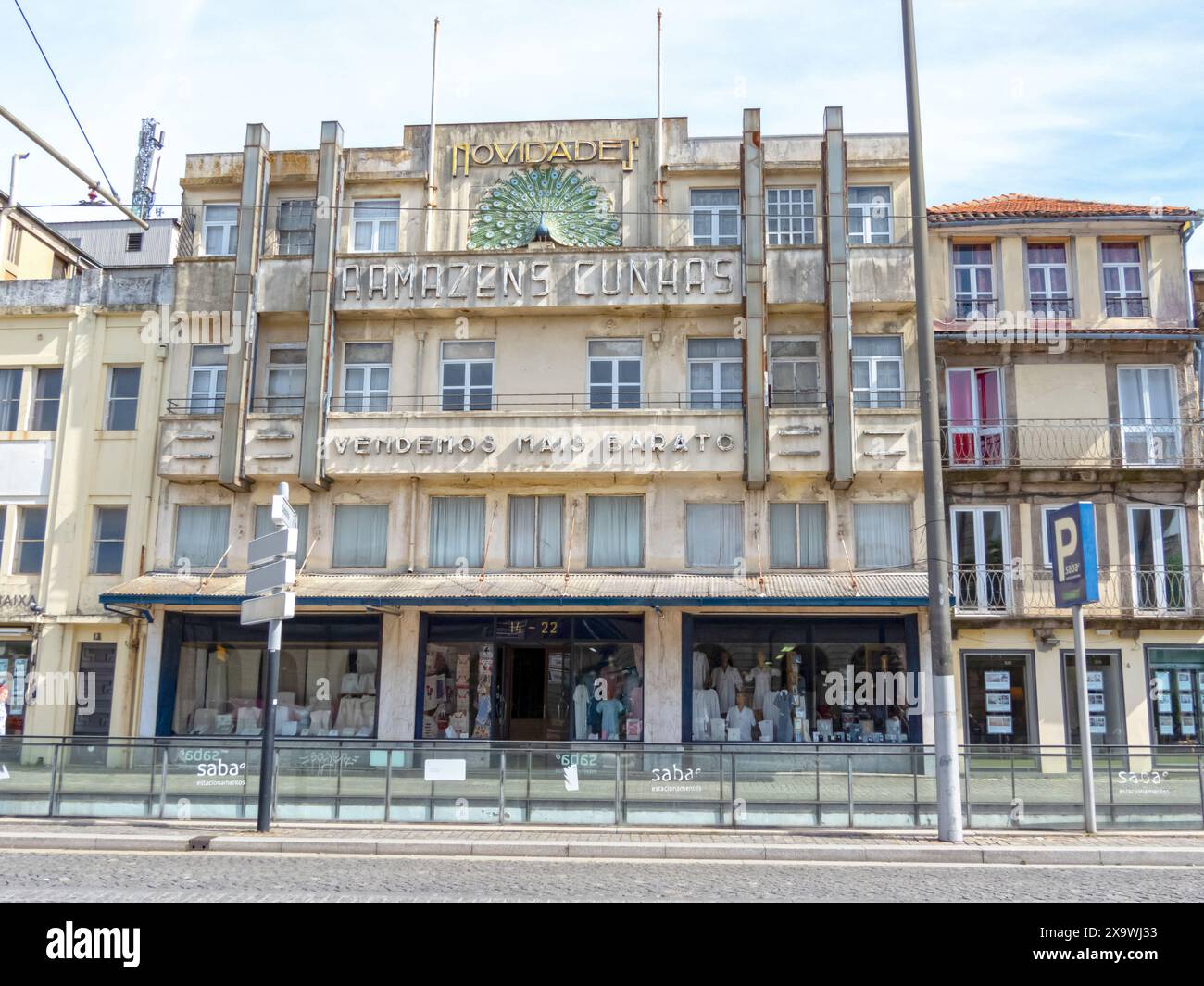 PORTO, PORTUGAL - 24 AVRIL 2024 : bâtiment Art Déco de la boutique de textile Armazens Cunhas avec paon coloré et devise «nous vendons moins cher» sur la façade à Por Banque D'Images