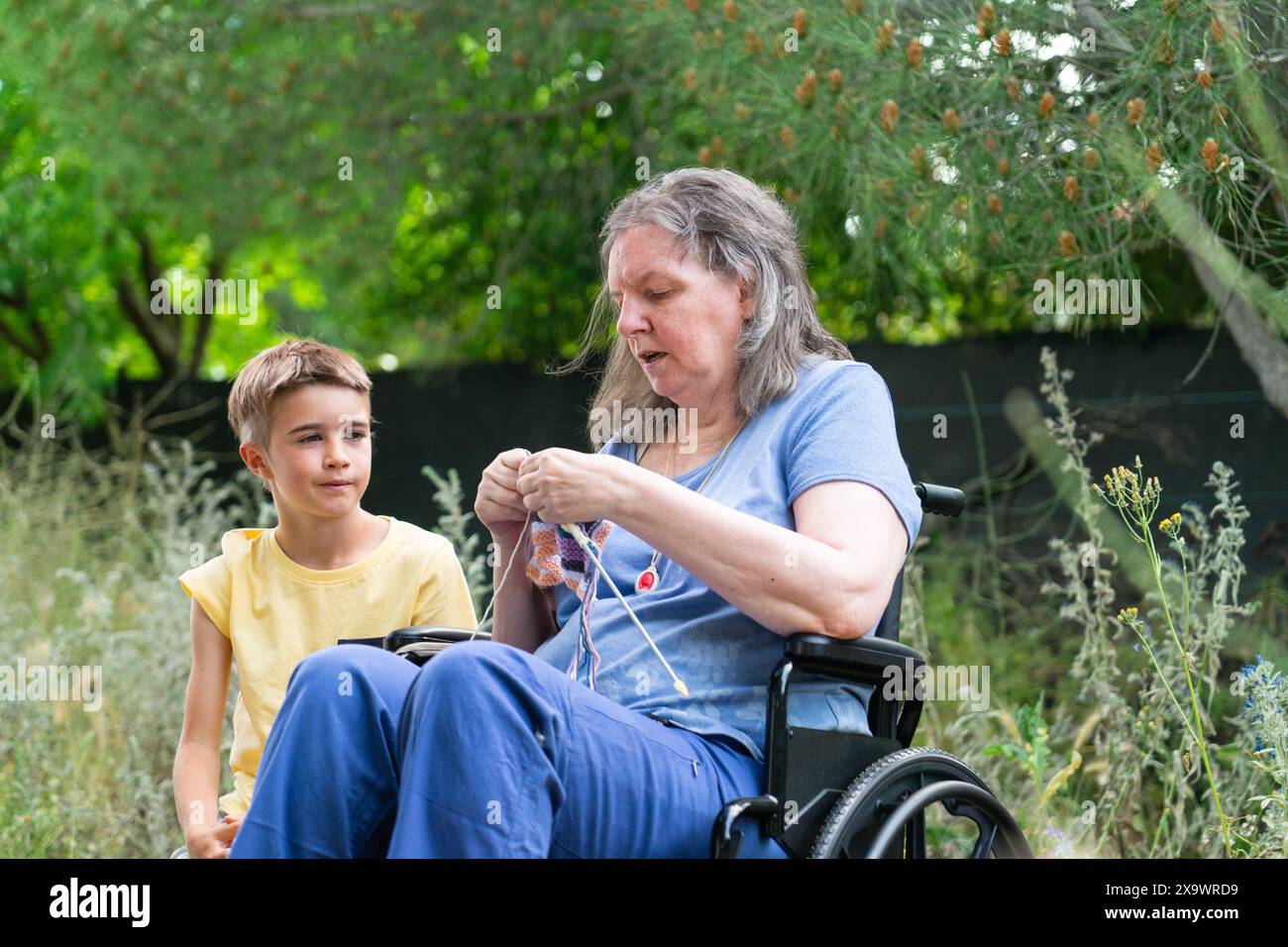 grand-mère de 65 ans tricote à l'extérieur en compagnie de son petit-fils de 8 ans Banque D'Images