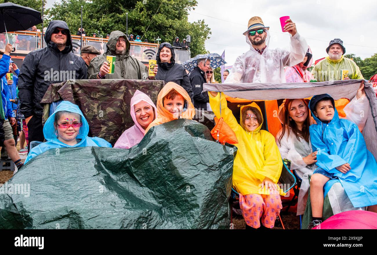 Un groupe joyeux et coloré se met à l’abri des fortes pluies au Latitude Festival à Henham Park dans le Suffolk. Banque D'Images