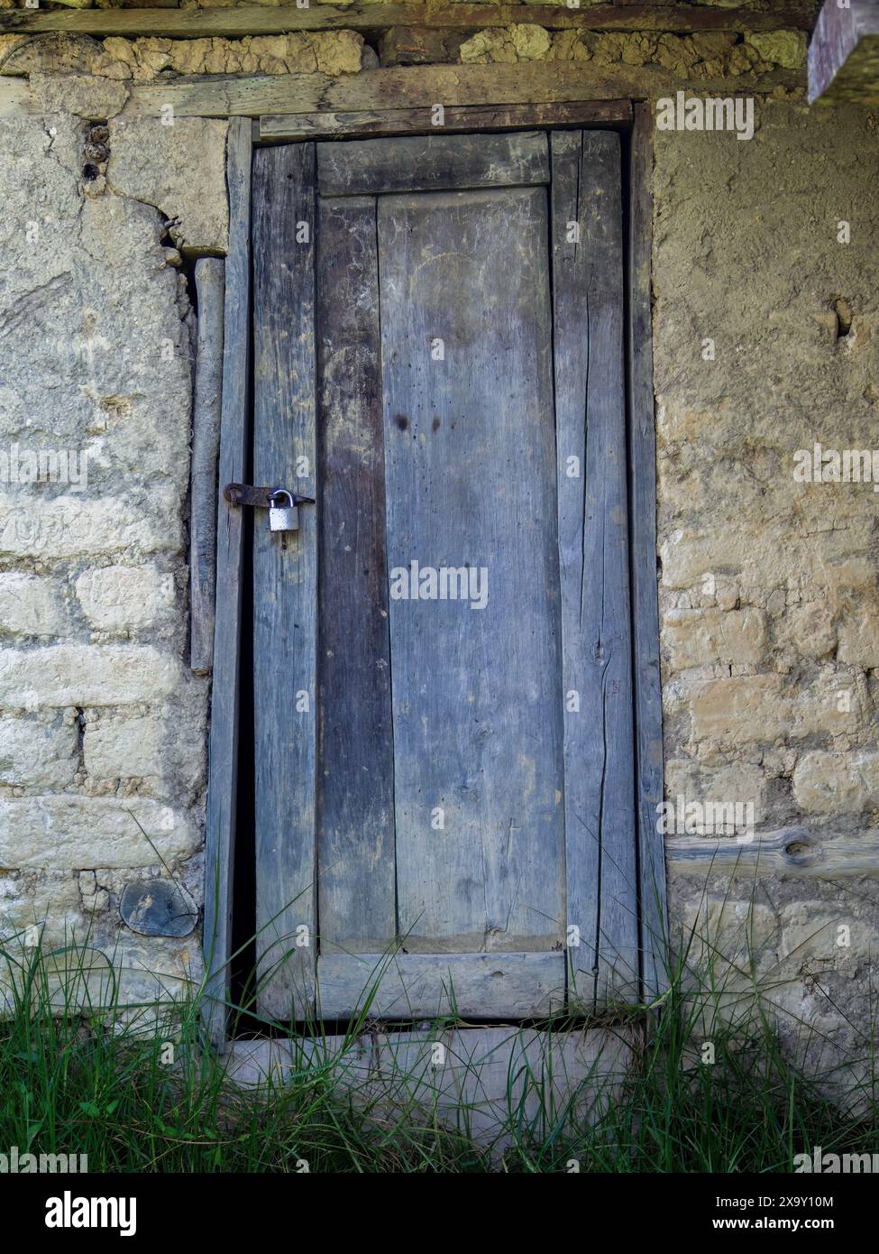 La porte en bois altérée d'un ancien hangar en adobe, dans une ferme des montagnes andines orientales du centre de la Colombie. Banque D'Images