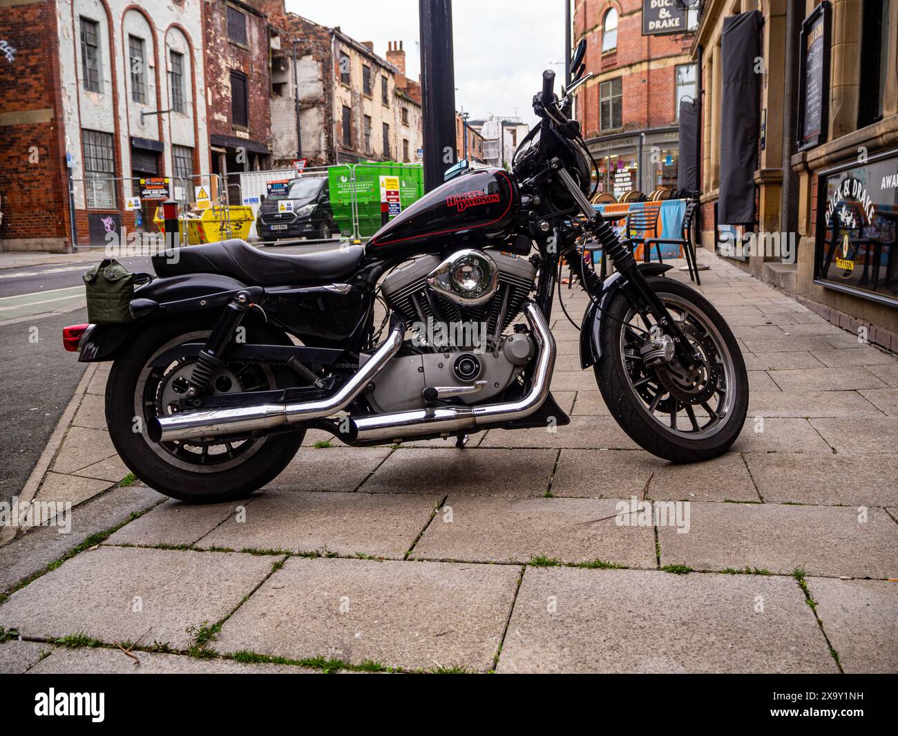 Moto Harley-Davidson garée sur le trottoir à l'extérieur d'un pub dans le centre-ville de Leeds, avec la reconstruction d'un centre-ville en cours derrière. Banque D'Images