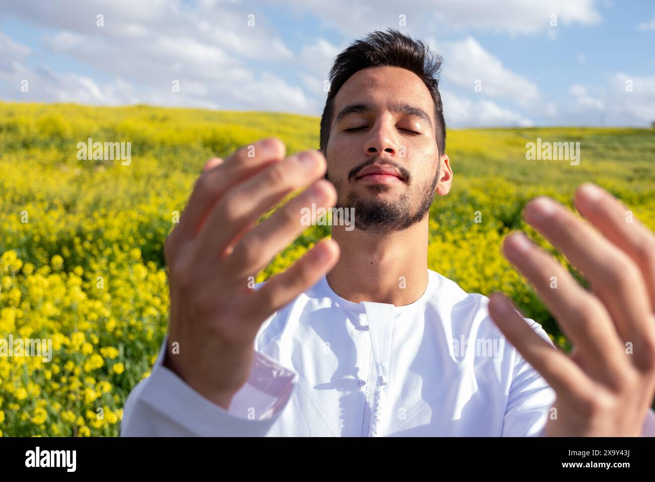 Un peuple arabe profite d'un pique-nique printanier dans une prairie près d'Abu Dhabi. Assis sur des chaises, ils savourent des tasses de café sous un ciel bleu avec des nuages éparpillés Banque D'Images