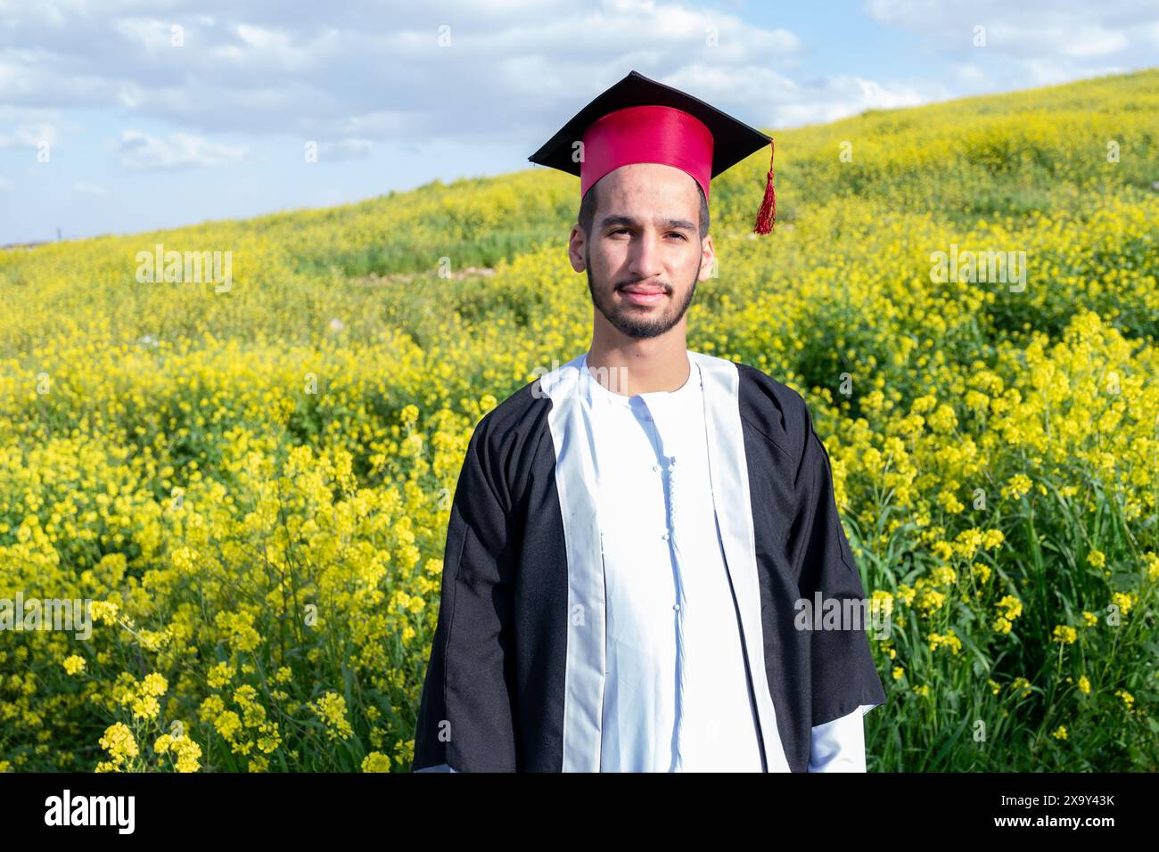 Jeune homme arabe célébrant sa remise des diplômes avec des roses autour et un look naturel Banque D'Images