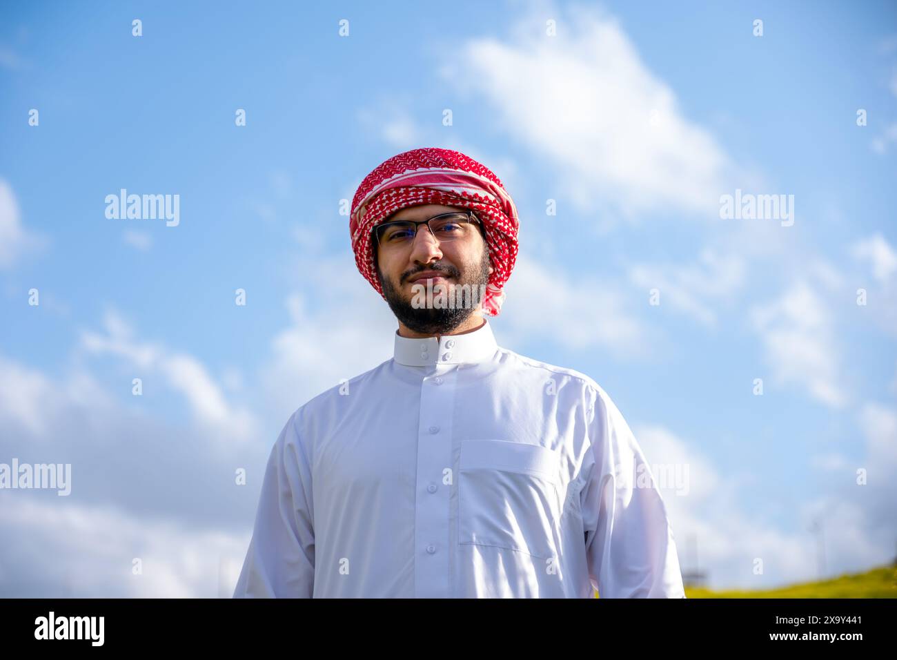 Un peuple arabe profite d'un pique-nique printanier dans une prairie près d'Abu Dhabi. Assis sur des chaises, ils savourent des tasses de café sous un ciel bleu avec des nuages éparpillés Banque D'Images