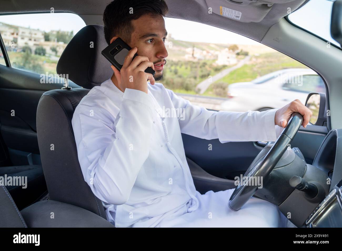 Jeune homme arabe utilisant le téléphone portable en conduisant Banque D'Images