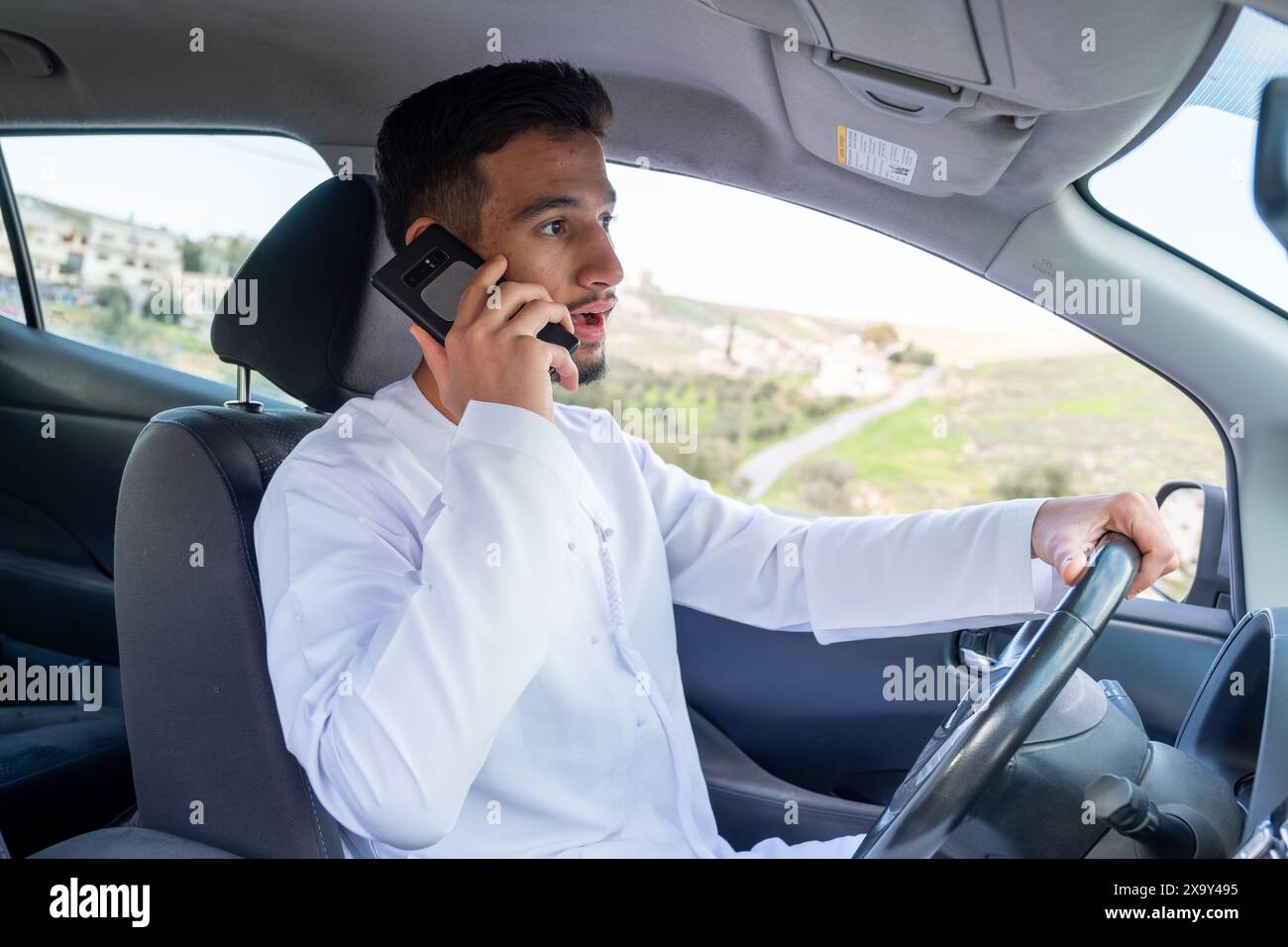 Jeune homme arabe utilisant le téléphone portable en conduisant Banque D'Images