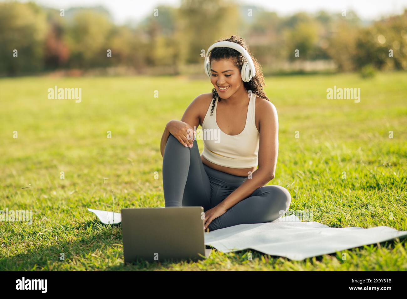 Femme profitant de la séance de yoga du matin dans le parc tout en diffusant en ligne Banque D'Images