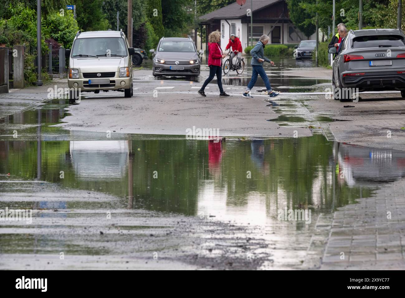 03 juin 2024, Bavière, Baar-Ebenhausen : les habitants traversent une rue inondée dans leur quartier. Photo : Peter Kneffel/dpa - ATTENTION : les plaques d'immatriculation de la voiture ont été pixelisées pour des raisons légales Banque D'Images