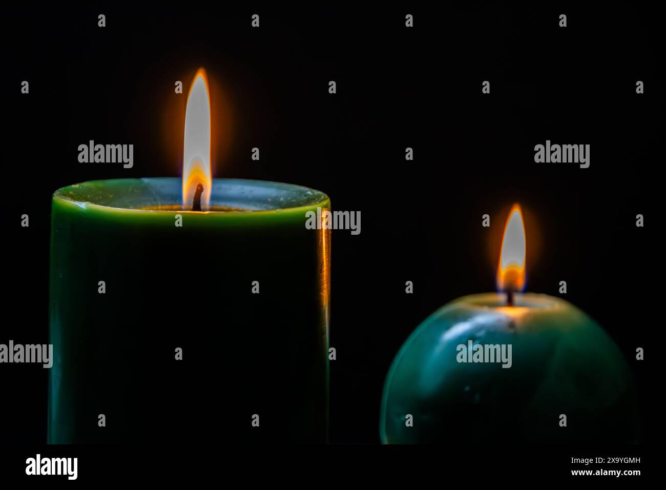 Les deux bougies vertes groupées sur une surface sombre. Banque D'Images