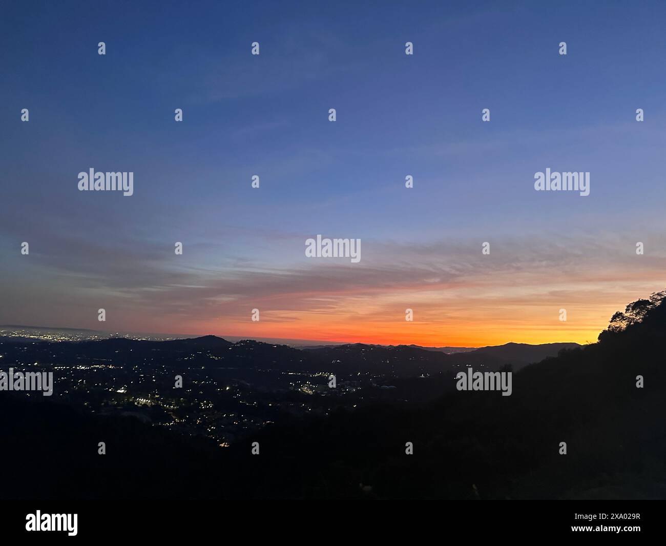 Un lever de soleil sur les montagnes et la ville la nuit Banque D'Images