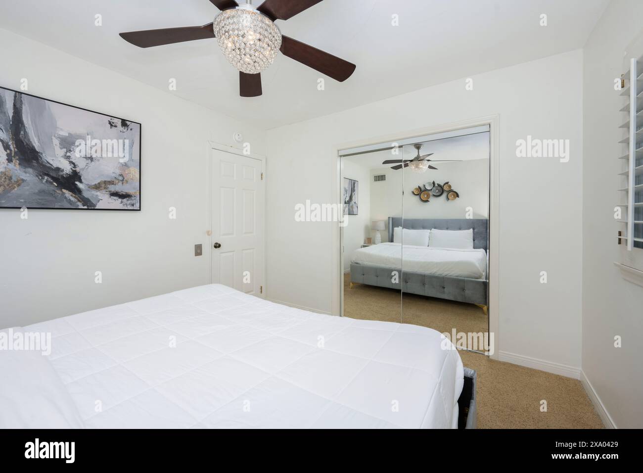 Une chambre minimaliste avec lit blanc, ventilateur de plafond brun et art mural à Hidden Hills, CA Banque D'Images