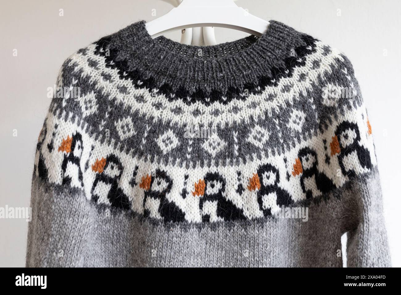 Photo en gros plan d'un grand empiècement coloré d'un pull lopapeysa en laine grise tricotée dans un motif de tricot d'oiseau macareux islandais traditionnel Banque D'Images