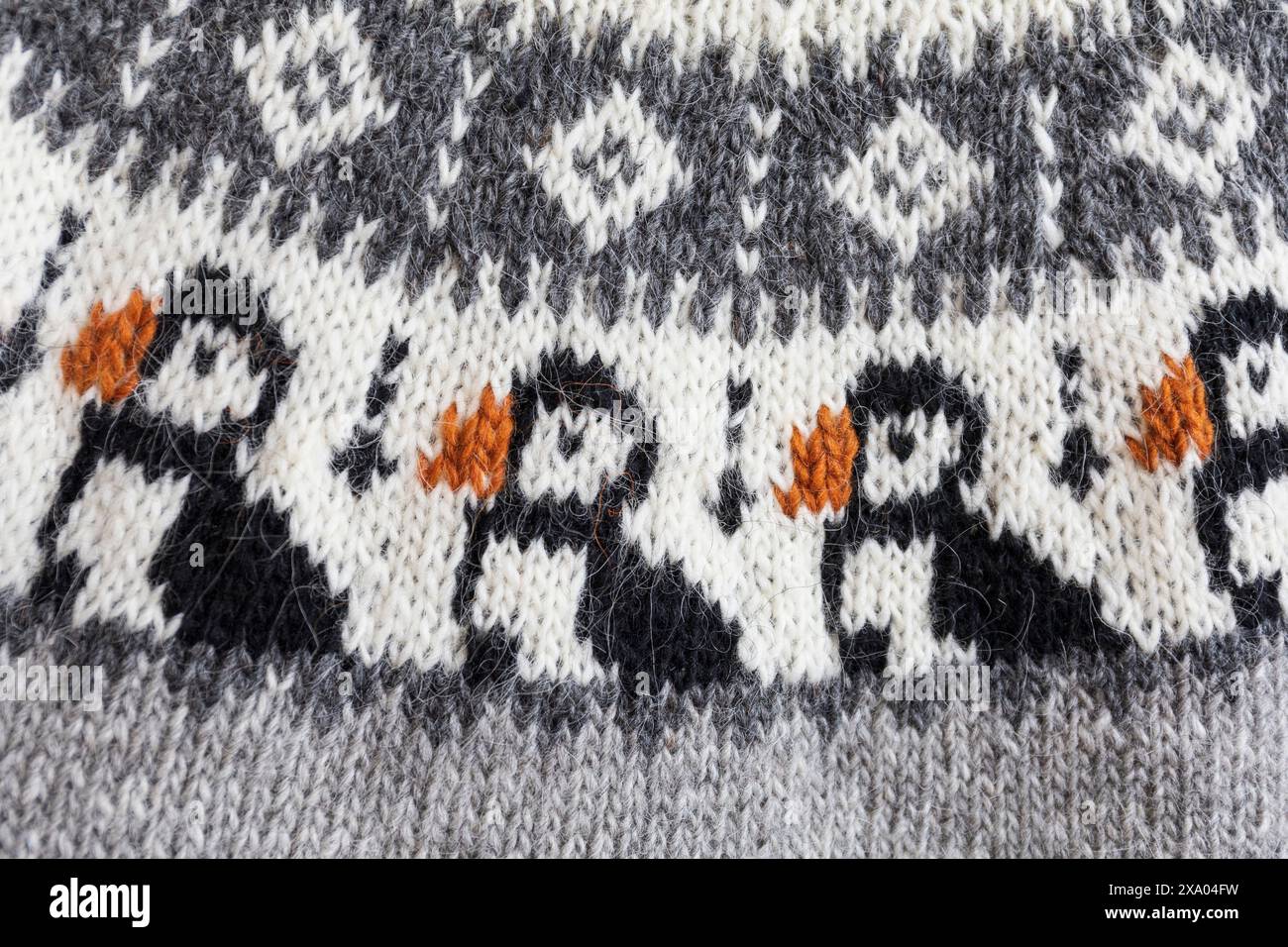 Photo en gros plan d'un grand empiècement coloré d'un pull lopapeysa en laine grise tricotée avec des oiseaux macareux islandais traditionnels Banque D'Images