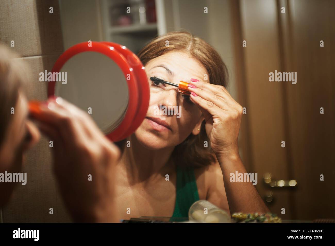 Une jeune femme rehaussant ses cils avec du mascara pendant sa routine beauté Banque D'Images