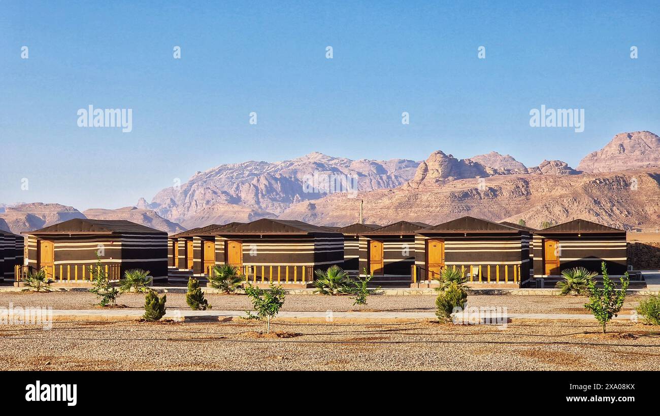 Une rangée de maisons sur la terre avec des montagnes lointaines à Wadi Rum, Jordanie Banque D'Images