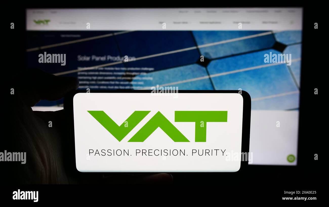 Personne tenant un téléphone portable avec le logo de la société suisse de technologie du vide VAT Group AG en face de la page Web de l'entreprise. Concentrez-vous sur l'affichage du téléphone. Banque D'Images