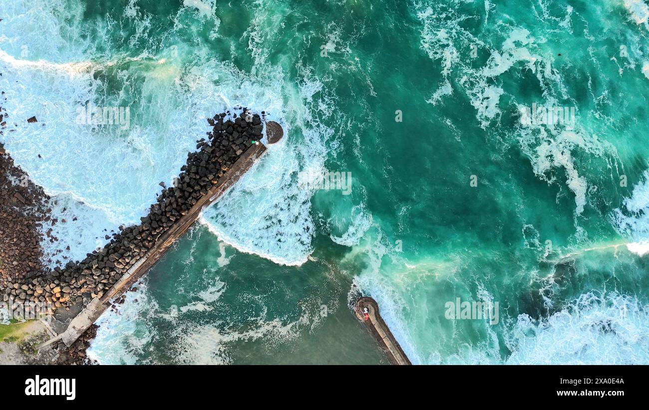 Une vue aérienne du mur accidenté des eaux pluviales avec des vagues vertes qui s'écrasent Banque D'Images