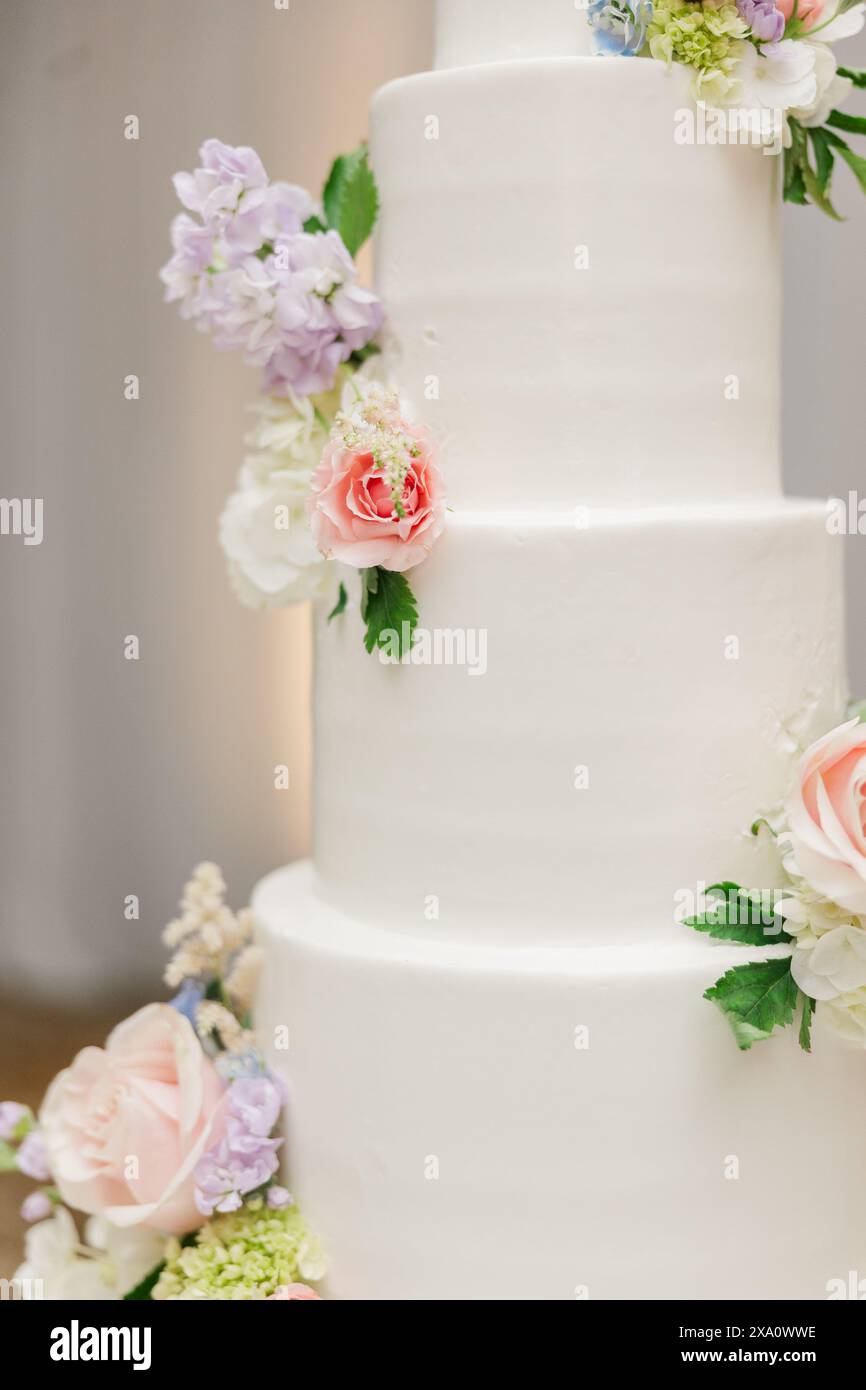 Un élégant gâteau de mariage blanc orné de fleurs Banque D'Images