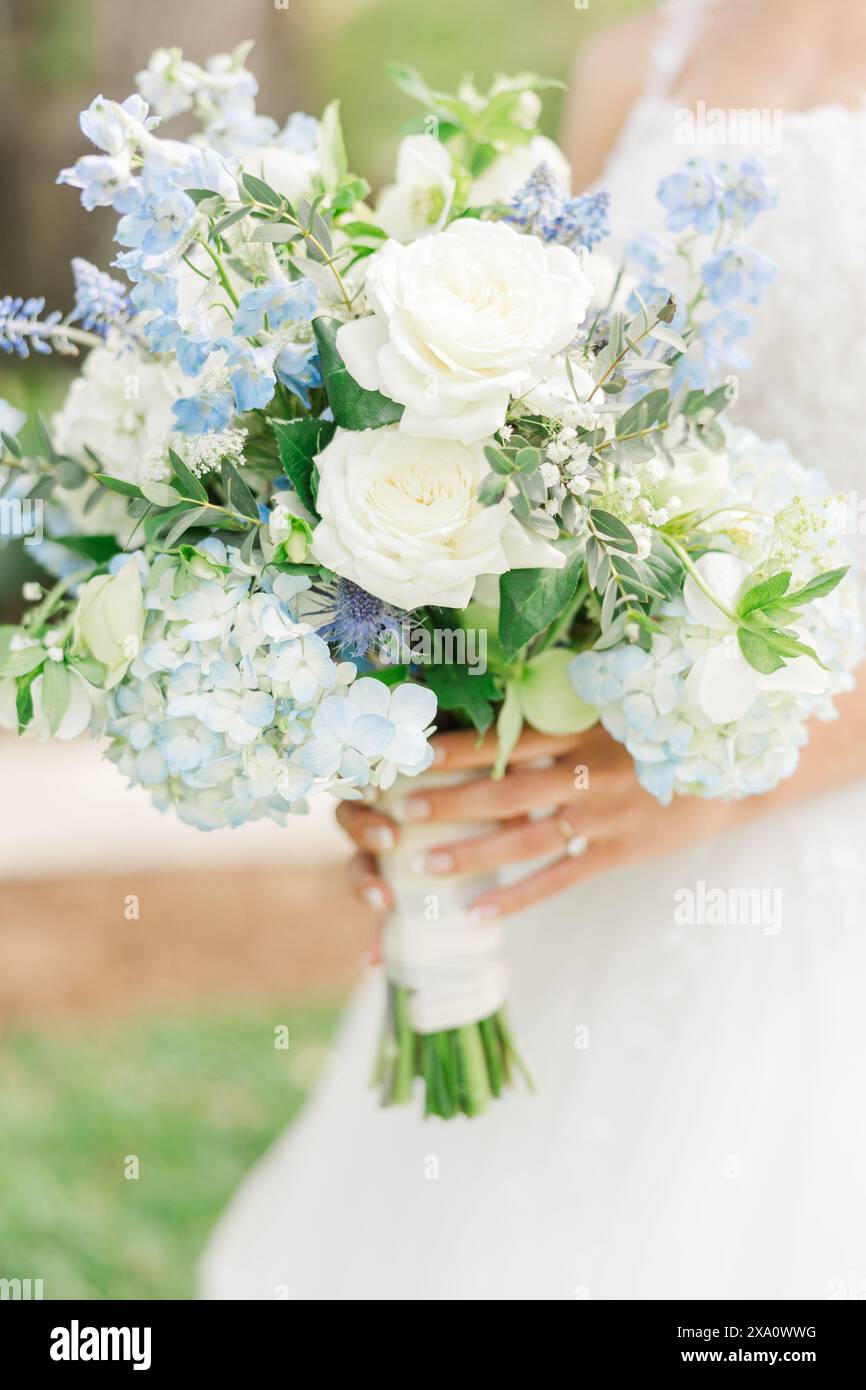 Un pont tenant un bouquet de fleurs blanches et bleues dans ses mains Banque D'Images