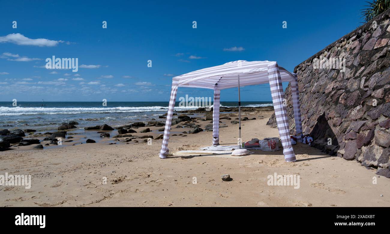 Une petite tente dressée près d'un mur de plage rocheux Banque D'Images