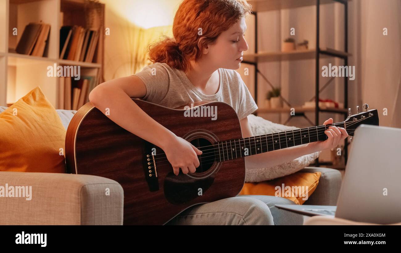Tutoriel guitare. Formation acoustique en ligne. Femme musicienne inspirée professionnelle enseignant l'instrument de jeu de cordes sur l'appel Internet portable à la maison. Banque D'Images
