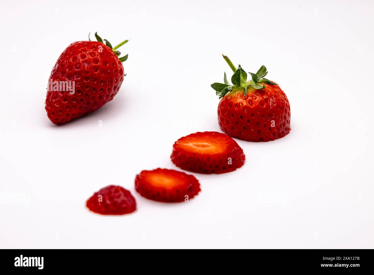 Fraises fraîches tranchées sur un fond blanc avec des tons rouges vibrants Banque D'Images