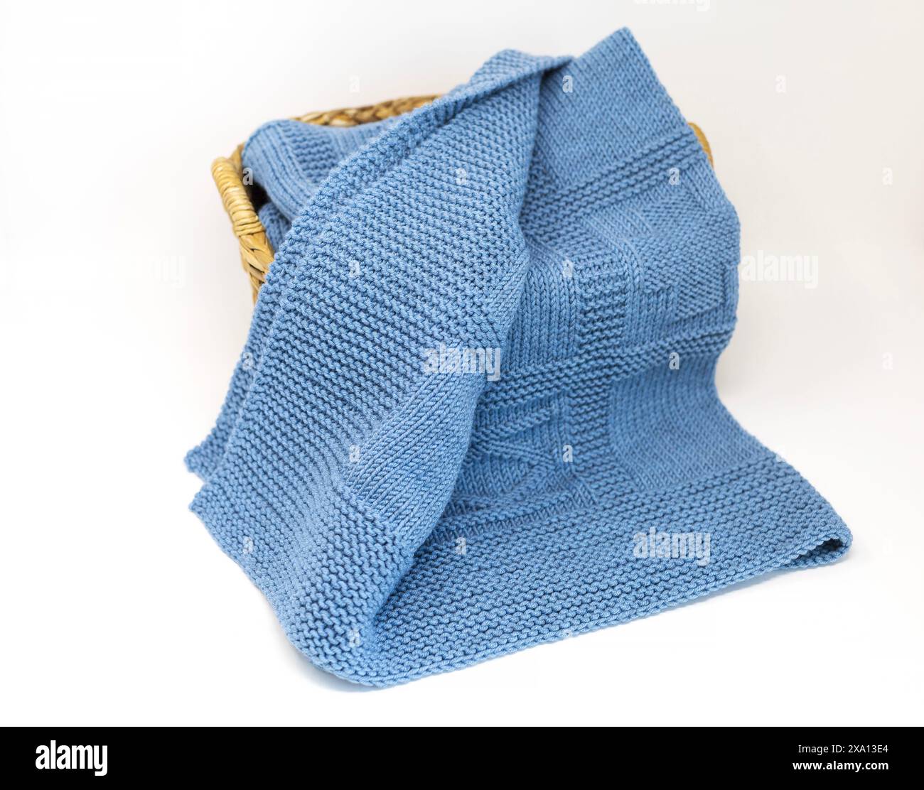 photographie vue de dessus d'une couverture tricotée à la main texturée en laine bleue dans un motif de tricotage géométrique dans un panier isolé sur un fond blanc Banque D'Images
