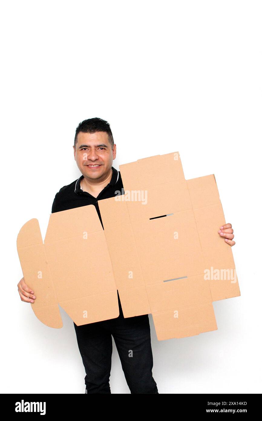 Homme adulte Latino à peau foncée assemble une boîte en carton suivant les instructions concentrée et attentive Banque D'Images Homme adulte Latino à peau foncée assemble une boîte en carton suivant les instructions concentrée et attentive Banque D'Images