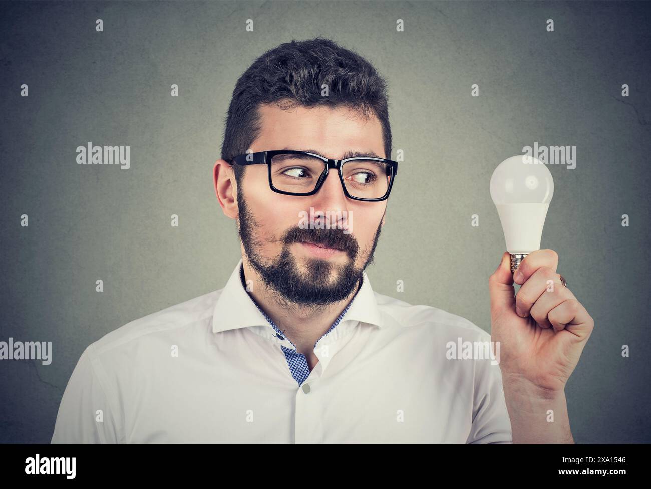 Homme regardant une ampoule économe en énergie Banque D'Images