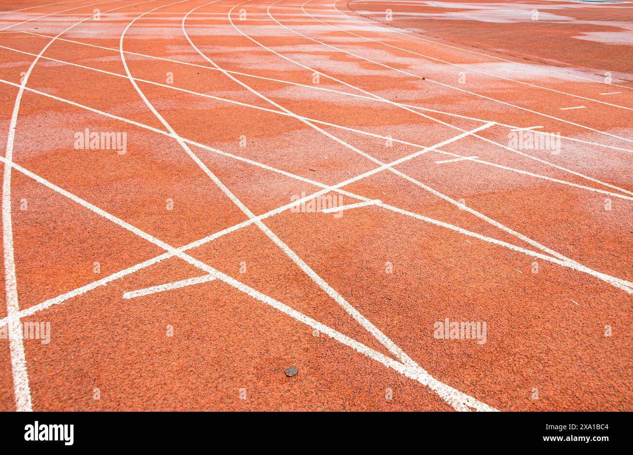 La piste rouge vif entrelace la trajectoire blanche droite avec la trajectoire blanche courbe. Banque D'Images