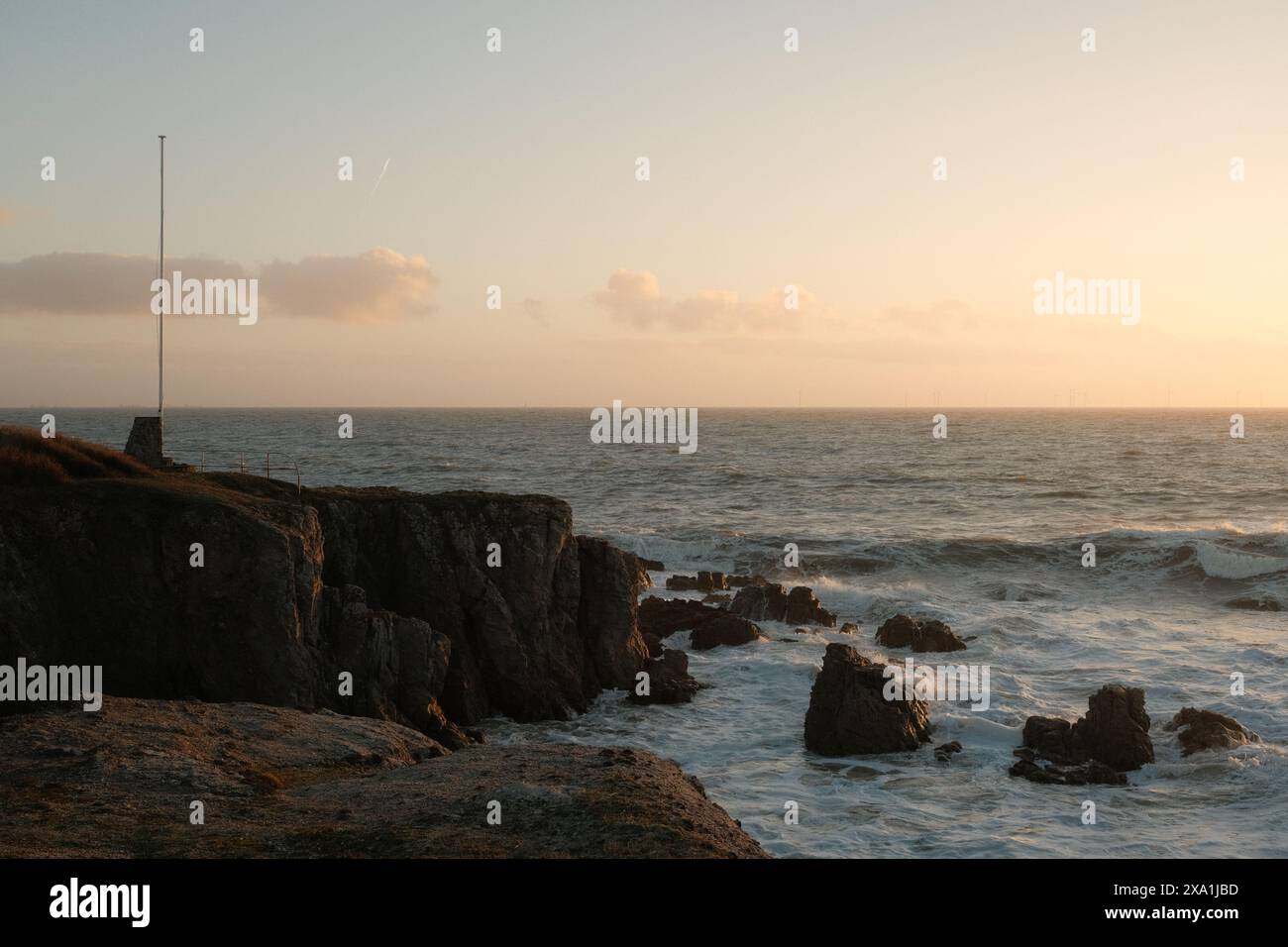 Le coucher de soleil illumine les vagues qui s'écrasent sur une rive rocheuse Banque D'Images