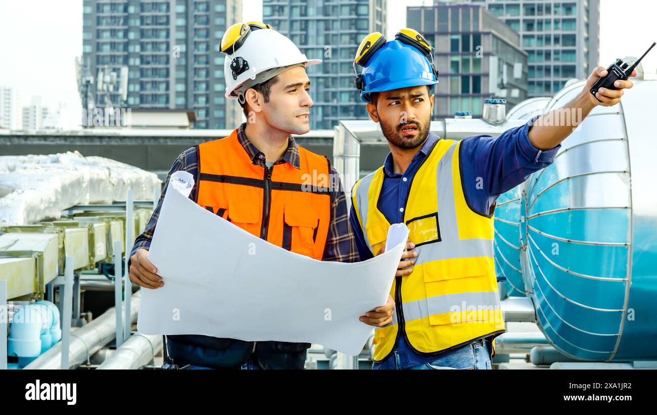 Les deux ouvriers de la construction en équipement de sécurité examinant les plans et discutant. Banque D'Images