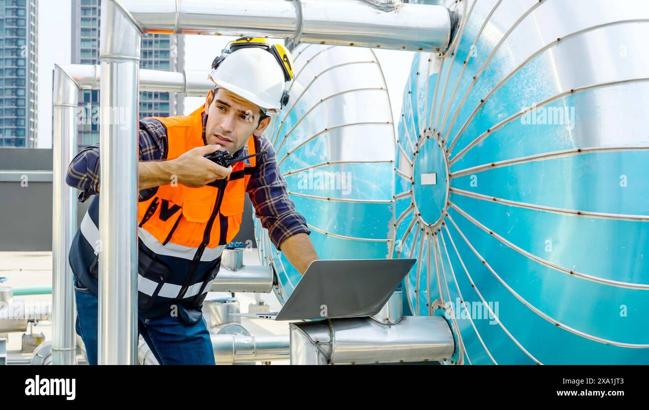 Travailleur en équipement de sécurité avec ordinateur portable et talkie-walkie sur le chantier de construction Banque D'Images