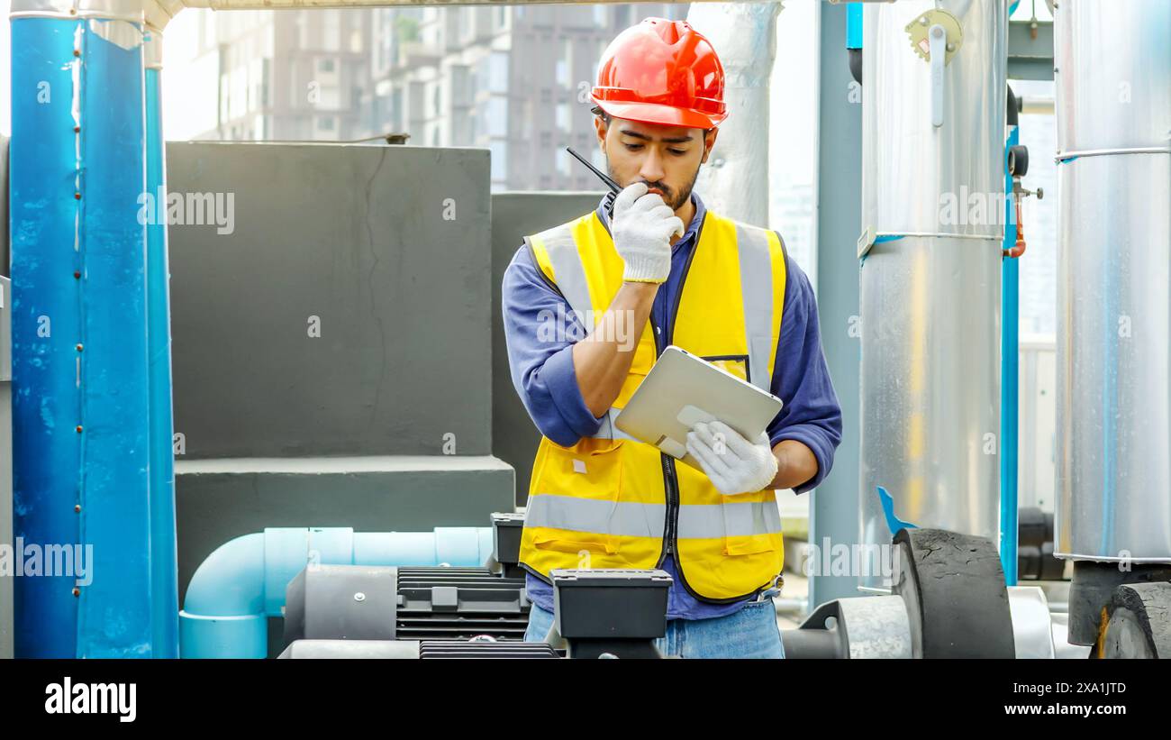 Travailleur en équipement de sécurité avec ordinateur portable et talkie-walkie sur le chantier de construction Banque D'Images