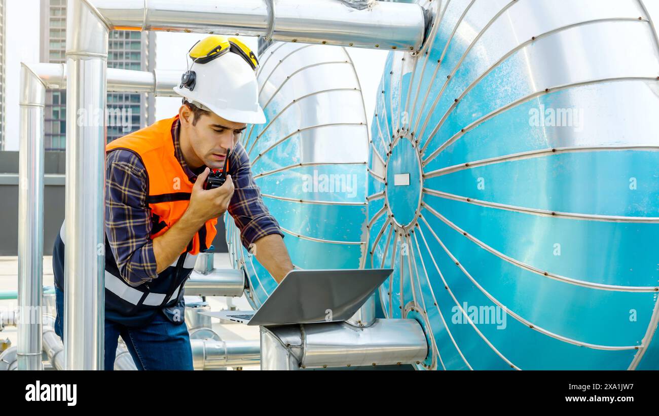 Travailleur en équipement de sécurité avec ordinateur portable et talkie-walkie sur le chantier de construction Banque D'Images