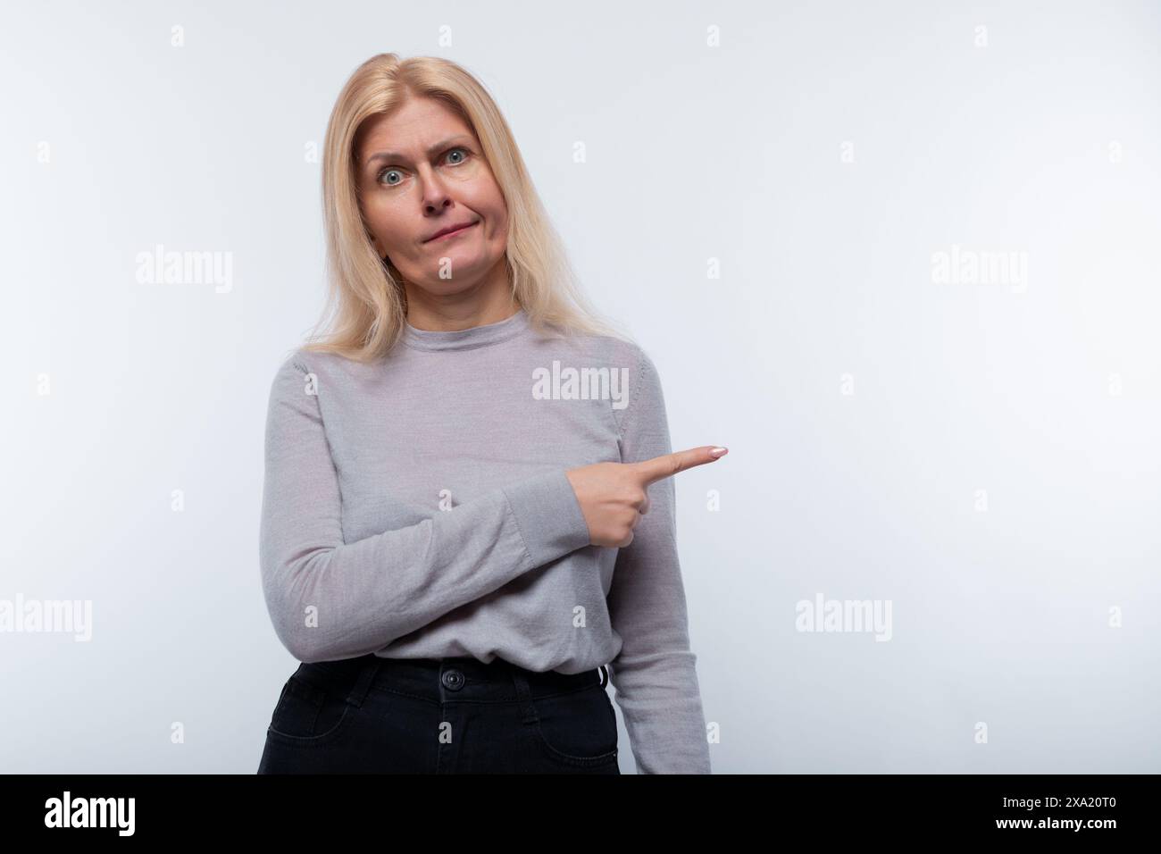 Une femme de 45 ans aux cheveux blonds pointe sa main vers un espace vide Banque D'Images