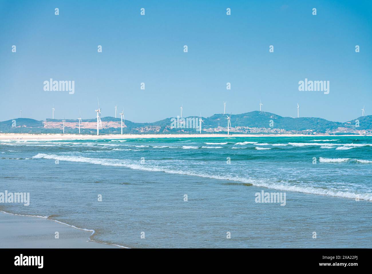 Une vue panoramique sur les éoliennes bordent une plage de sable avec des vagues qui s'écrasent sur le rivage Banque D'Images