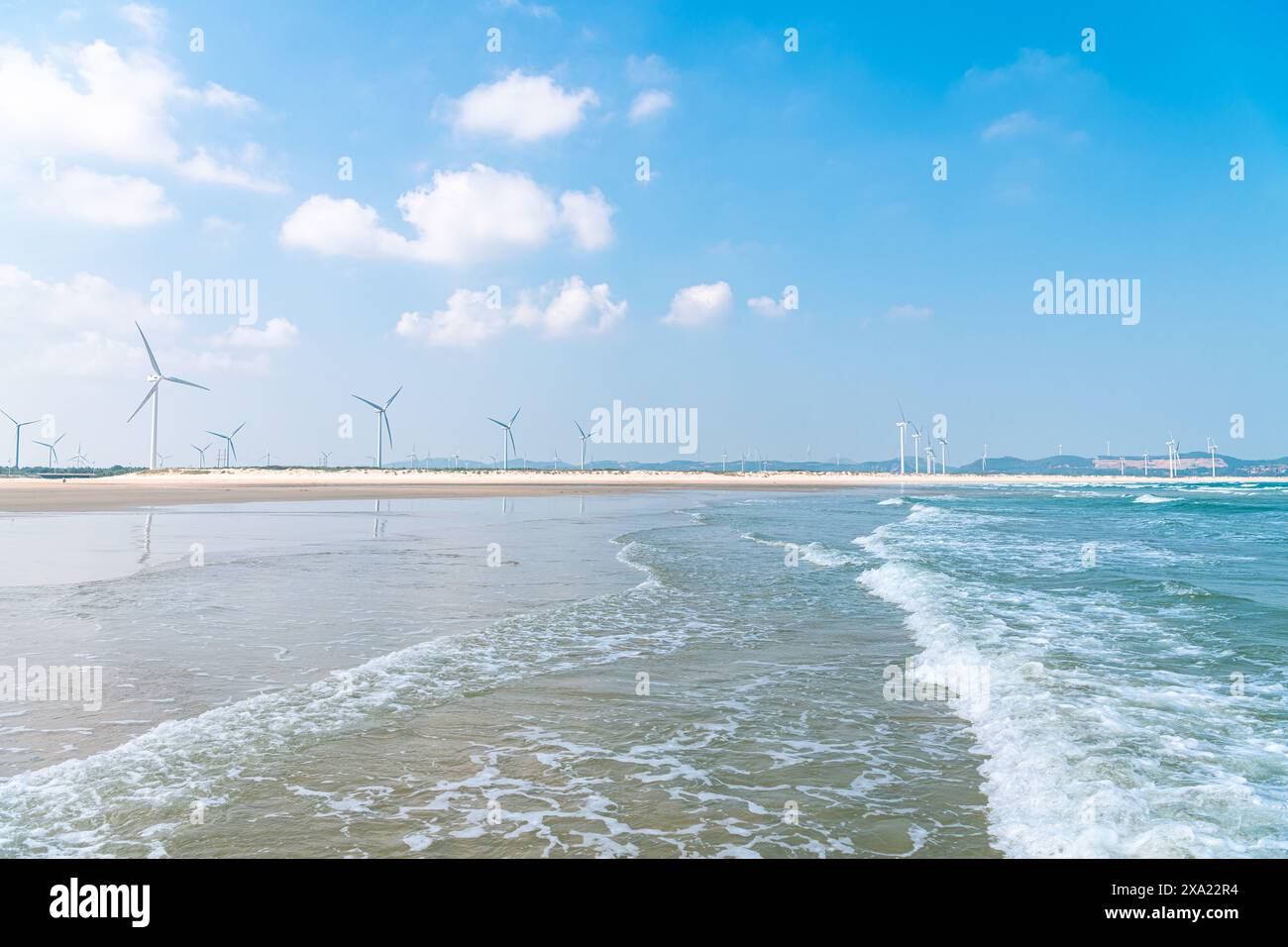 Une vue panoramique sur les éoliennes bordent une plage de sable avec des vagues qui s'écrasent sur le rivage Banque D'Images