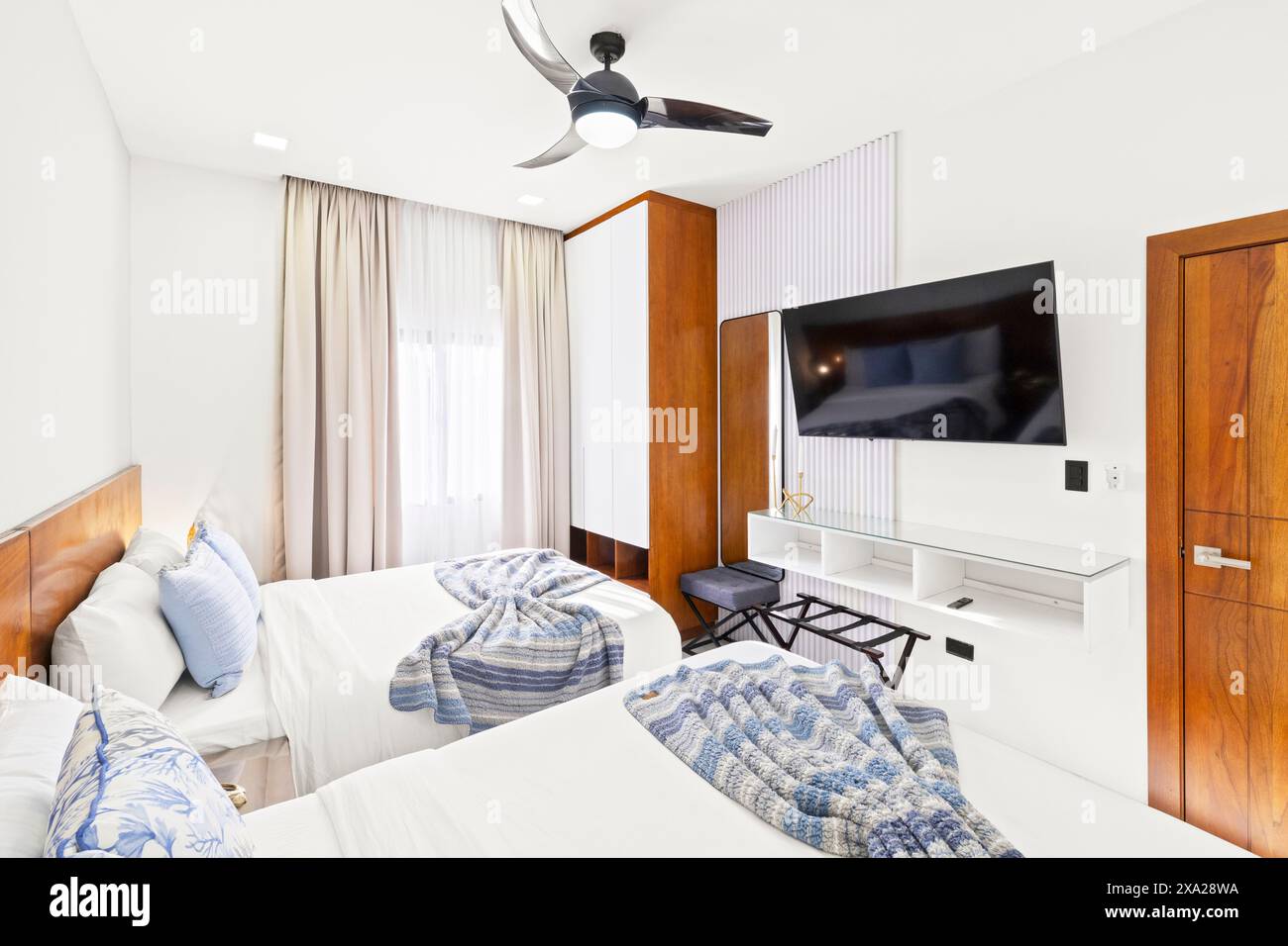 Une maison de vacances de luxe avec deux lits, un ventilateur de plafond et une télévision Banque D'Images