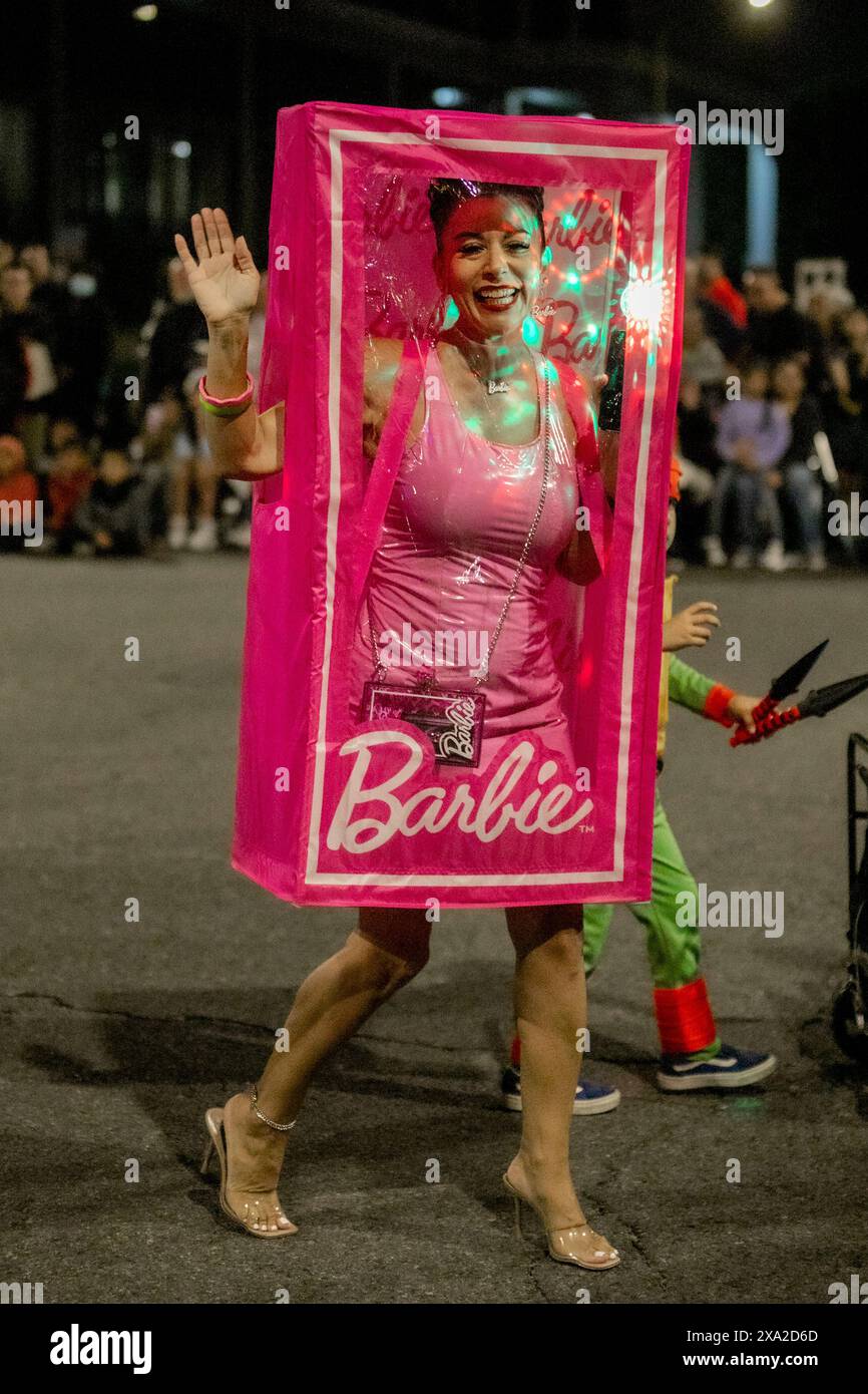 Marchant dans une parade nocturne d'Halloween à Anaheim, CA, un participant hispanique dépeint une poupée Barbie dans une boîte d'affichage de marque déposée. Banque D'Images